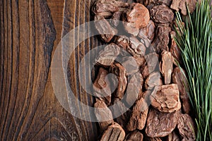 Pine bark and branch of pine tree on wooden board, top view.