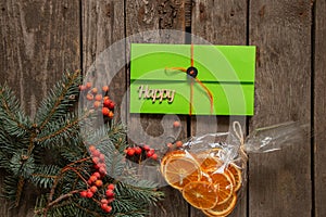 Pine branch and viburnum a bag with dried oranges and a green envelope with a gift lie on an old wooden background, new
