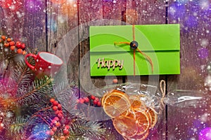 Pine branch and viburnum a bag with dried oranges and a green envelope with a gift lie on an old wooden background, New