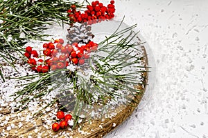 Pine bumps and branches with red rowan on an old snow-covered table