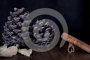 Pine cones. bay leaves and cinnamon sticks on a wooden table, close up