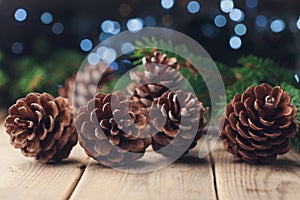 Pine cones and fir tree branch on rustic wooden table. Christmas greeting card.