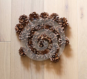 pine cones grouped on light oak wooden background, flat lay