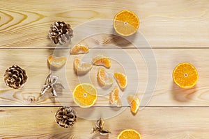 Pine cones, juicy cut and peeled tangerines lie on wooden table