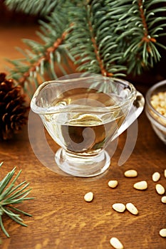 Pine nut oil and bowl of pine nuts on wooden background with cones, cedar brunches