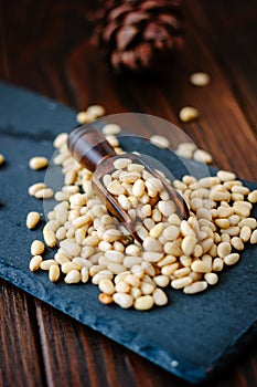 Pine nuts on a black slate with wooden scoop