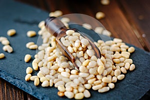 Pine nuts on a black slate with wooden scoop