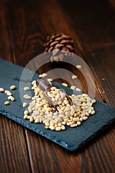 Pine nuts on a black slate with wooden scoop