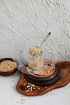 Pine nuts in a glass jar on wooden boards on a concrete background.