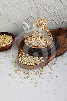 Pine nuts in a glass jar on wooden boards on a concrete background.