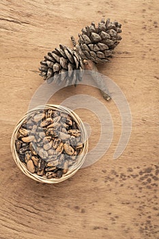 Pine nuts, kernels and cone on wooden table