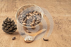 Pine nuts, kernels and cone on wooden table