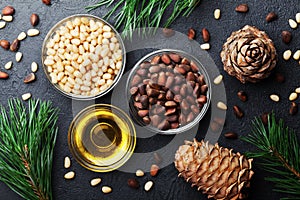 Pine nuts, oil and cedar cones on black table top view. Organic and healthy superfood.