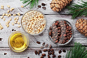 Pine nuts, oil and cedar cones on rustic wooden background top view. Organic and healthy superfood.