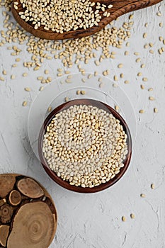 Pine nuts in a wooden bowl on cutting boards on a concrete background