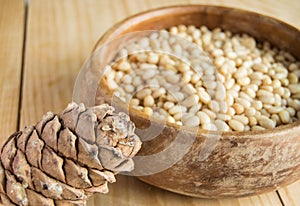 Pine nuts in a wooden bowl on a light wooden background, natural organic food, veganism