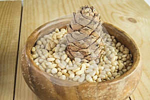 Pine nuts in a wooden bowl on a light wooden background, natural organic food, veganism