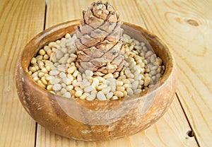 Pine nuts in a wooden bowl on a light wooden background, natural organic food, veganism