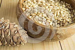 Pine nuts in a wooden bowl on a light wooden background, natural organic food, veganism