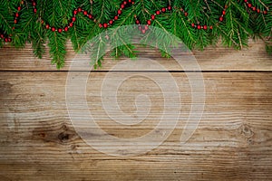 Pine tree border with red garland on old wooden background
