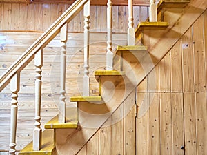 A pine wooden staircase with white balusters in a cozy home. Wooden Staircase in a Rustic Interior Setting