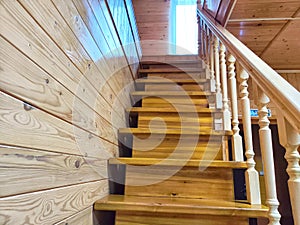 A pine wooden staircase with white balusters in a cozy home. Wooden Staircase in a Rustic Interior Setting