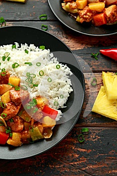 Pineapple and Chicken in sweet and sour sauce with bell pepper, rice and spring onion in black plate