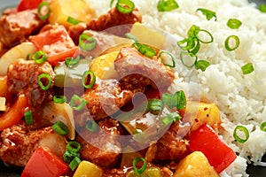 Pineapple and Chicken in sweet and sour sauce with bell pepper, rice and spring onion in black plate