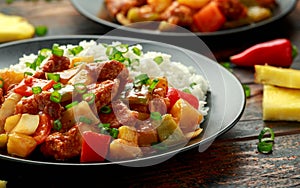 Pineapple and Chicken in sweet and sour sauce with bell pepper, rice and spring onion in black plate