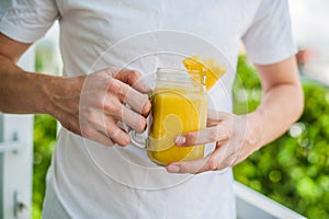 Pineapple cocktail with a slice of in the hands man on the terrace. Tropical concept