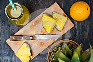 Pineapple on a dark wooden table and pineapple slices on a cutting board