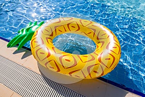 Pineapple float ring at blue swimming pool