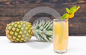 Pineapple and glass of fresh juice with straw