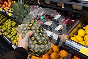 Pineapple in the hands of the buyer in grocery store.