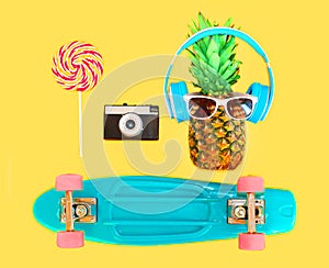 Pineapple with headphones sunglasses lollipop caramel vintage camera skateboard over colorful yellow