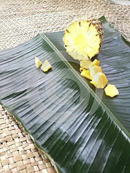 Pineapple and its slices placed in a green banana leaf