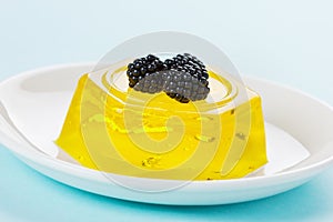 Pineapple jelly pudding decorated blackberries on a white plate