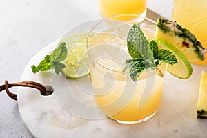 Pineapple juice cocktail with lime garnished with a mint leaf