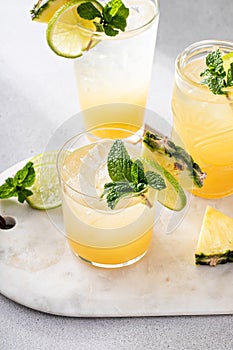 Pineapple juice cocktail with lime garnished with a mint leaf