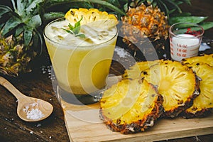 Pineapple juice and pineapple slices cut into pieces on a wooden table. Healthy wood fiber helps to reduce food. Pineapple juice