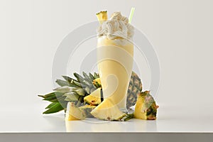 Pineapple milkshake with cream decorated with fruit on table isolated