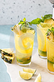 Pineapple mojito with mint and lime wedges garnished with mint leaves and pineapple slices