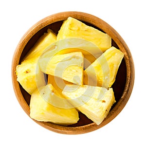 Pineapple pieces in wooden bowl over white