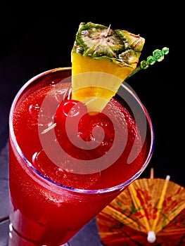 Pineapple red cocktail with cherry and umbrella