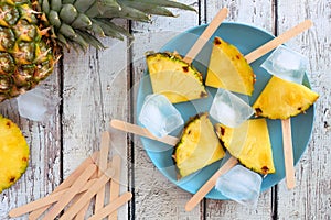 Pineapple slice popsicles, top view over white wood