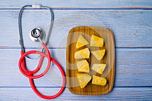 Pineapple sliced and stethoscope on wooden background . Care and healthy concept