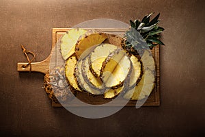 Pineapple. Sliced and whole pineapple on brown background, top vew