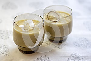 Pineapple smoothie with bananas, oatmeals and coconut milk, decorated with coconut chips, Christmas breakfast, white tablecloth