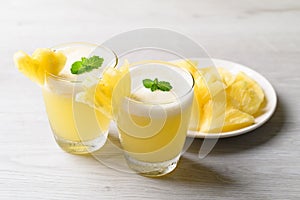 Pineapple smoothie in glass with sliced pineapple fruit, summer drink