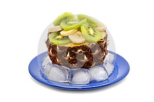 Pineapple stuffed with chopped banana and kiwi on a blue plate with ice cubes